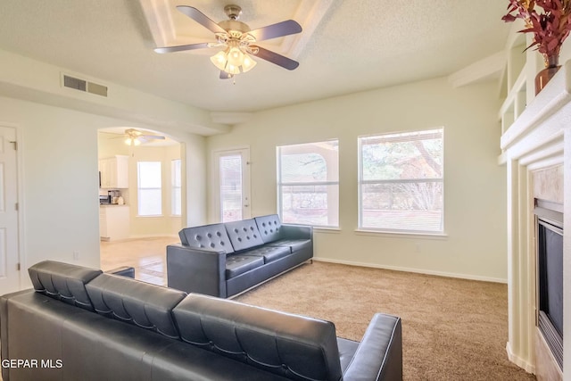 carpeted living room with ceiling fan and a textured ceiling