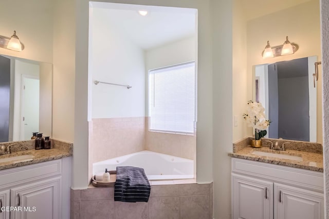 bathroom with vanity and tiled tub