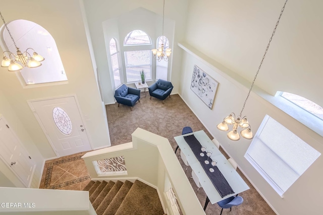 foyer entrance featuring carpet flooring, a high ceiling, and a chandelier