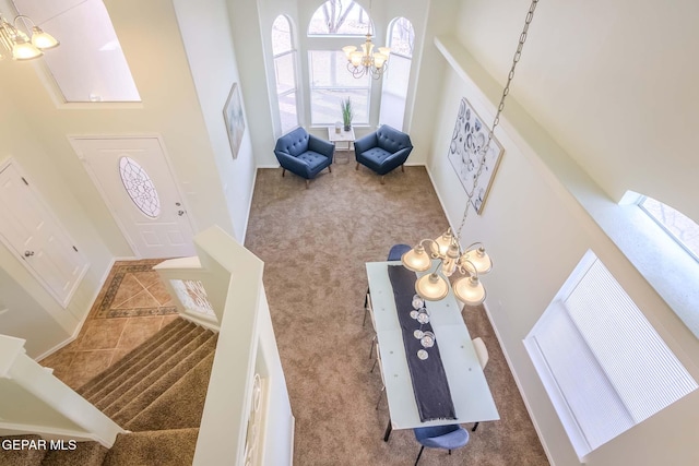 entryway featuring carpet floors, a high ceiling, and a chandelier