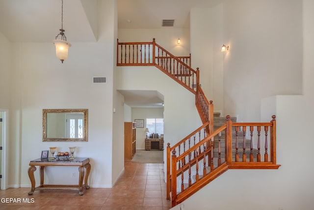 stairway with a high ceiling and tile patterned flooring