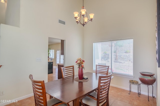 dining area featuring a chandelier, light tile patterned flooring, and a high ceiling