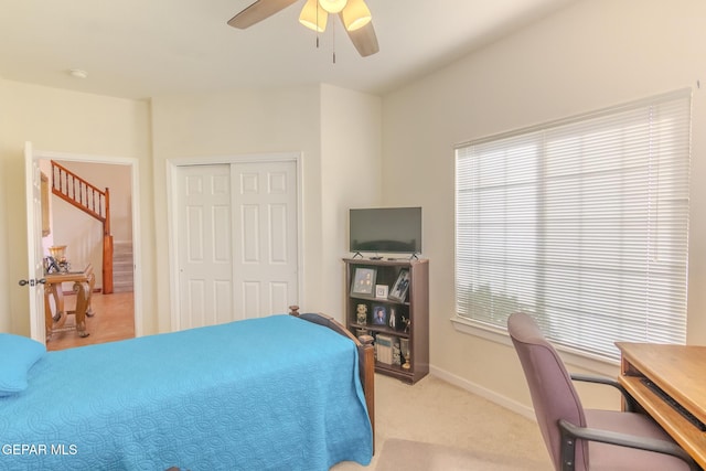 carpeted bedroom featuring ceiling fan and a closet