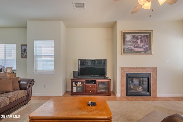 carpeted living room with a tiled fireplace and ceiling fan