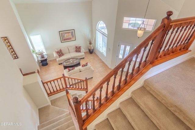 staircase featuring carpet flooring and a towering ceiling