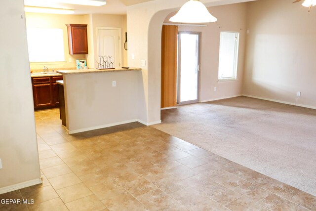 kitchen with ceiling fan, sink, pendant lighting, and light carpet