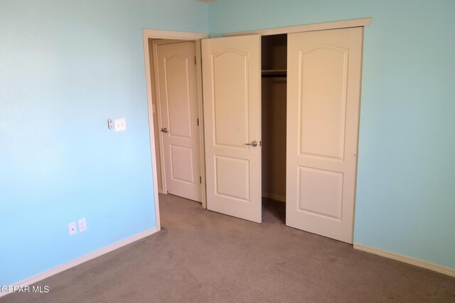 unfurnished bedroom with a closet and light colored carpet