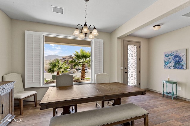 dining area with light wood-type flooring and a notable chandelier