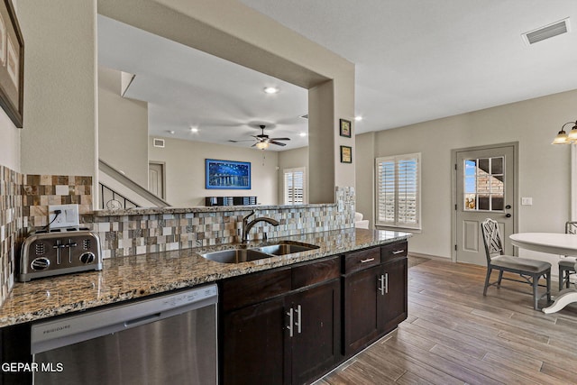 kitchen with dark brown cabinetry, sink, stone countertops, backsplash, and stainless steel dishwasher