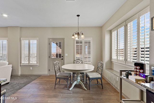 dining space featuring hardwood / wood-style floors, a healthy amount of sunlight, and an inviting chandelier