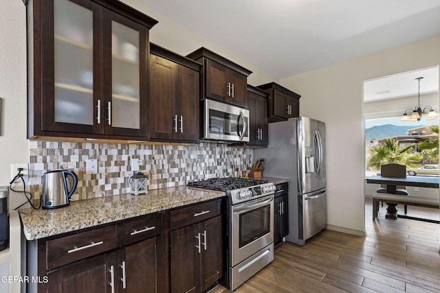 kitchen featuring light stone counters, decorative backsplash, dark brown cabinetry, and stainless steel appliances