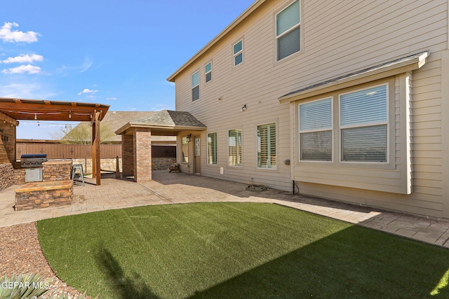 back of property with an outdoor kitchen, a lawn, and a patio area