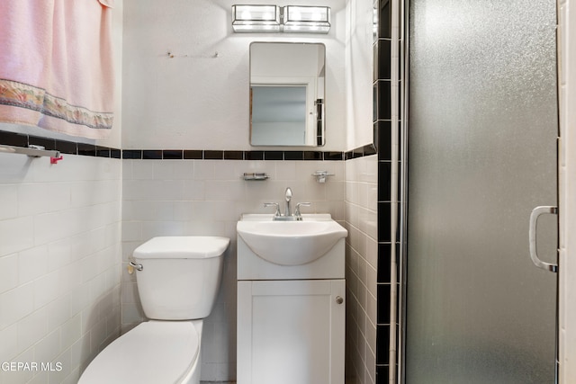 bathroom with vanity, toilet, an enclosed shower, and tile walls