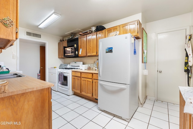 kitchen featuring sink, white appliances, and light tile patterned floors