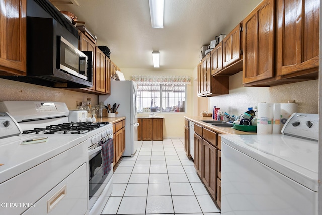3405 Volcanic Ave, El Paso, TX 79904 - kitchen with white appliances, brown cabinets, light countertops, and light tile patterned floors