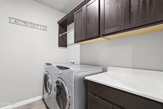 washroom with cabinets, separate washer and dryer, and wood-type flooring