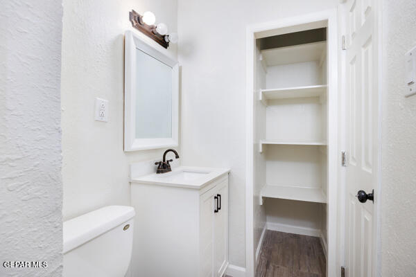 bathroom featuring toilet, vanity, and hardwood / wood-style flooring