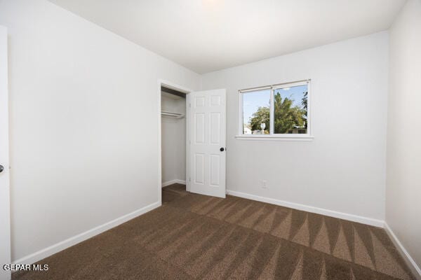 unfurnished bedroom with a closet and dark carpet