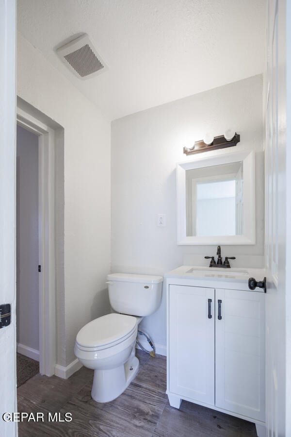 bathroom with wood-type flooring, vanity, and toilet