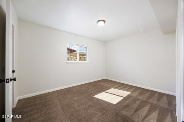 spare room with dark carpet