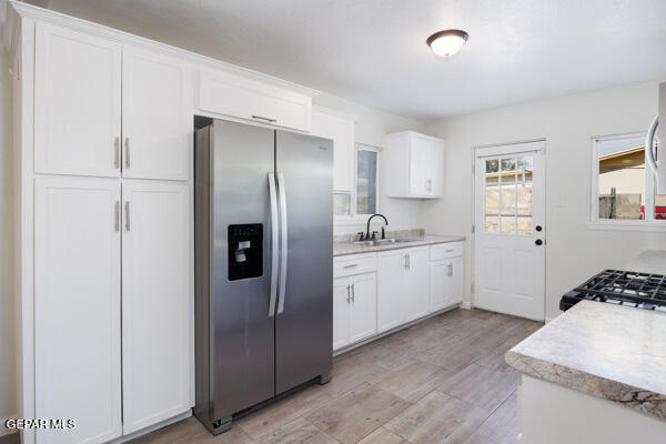 kitchen featuring white cabinetry, appliances with stainless steel finishes, sink, and light wood-type flooring