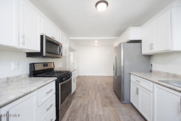 kitchen featuring stainless steel appliances, light stone countertops, white cabinetry, and light hardwood / wood-style flooring