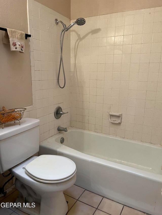 bathroom with toilet, tiled shower / bath, and tile patterned floors