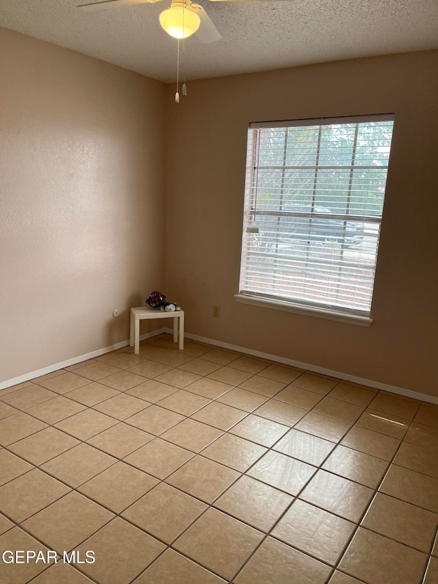 spare room featuring a textured ceiling, light tile patterned flooring, and ceiling fan