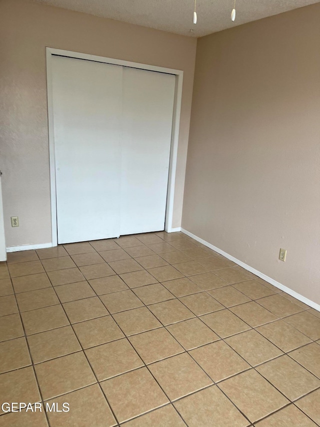 unfurnished bedroom with light tile patterned floors, a textured ceiling, and a closet