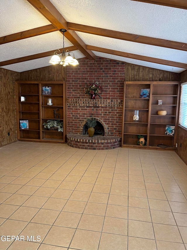 unfurnished living room featuring vaulted ceiling with beams, a fireplace, a textured ceiling, wooden walls, and an inviting chandelier