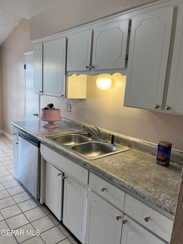 kitchen with vaulted ceiling, sink, stainless steel dishwasher, light tile patterned flooring, and white cabinetry