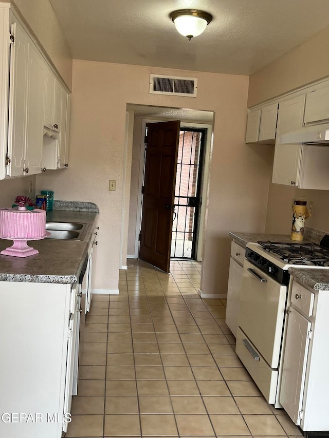 kitchen featuring white cabinets, white gas range, and light tile patterned flooring