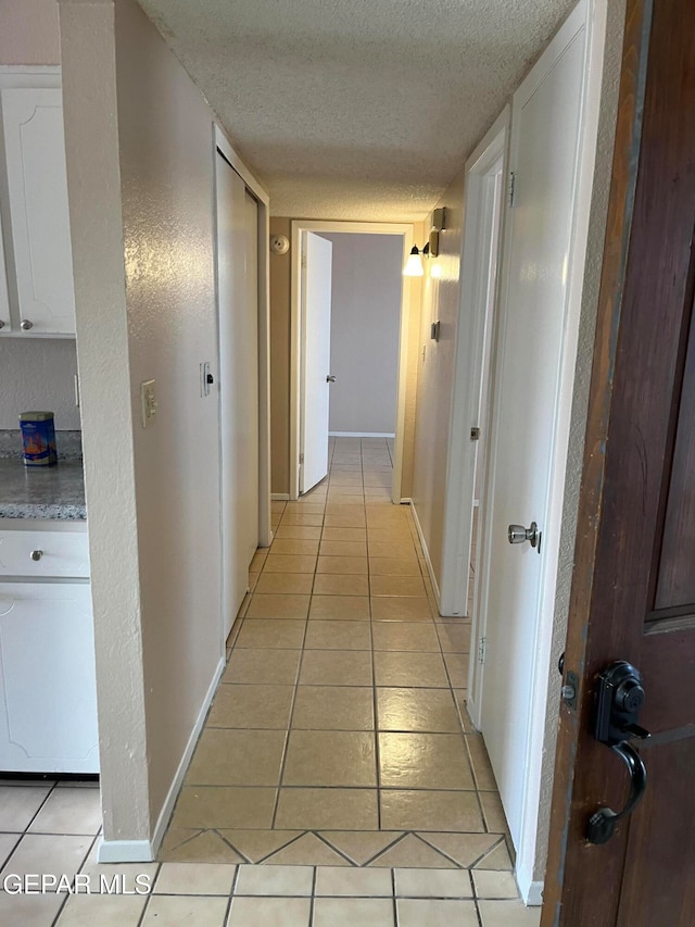 hallway featuring light tile patterned flooring and a textured ceiling