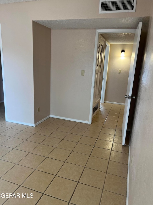 spare room with a textured ceiling and light tile patterned floors