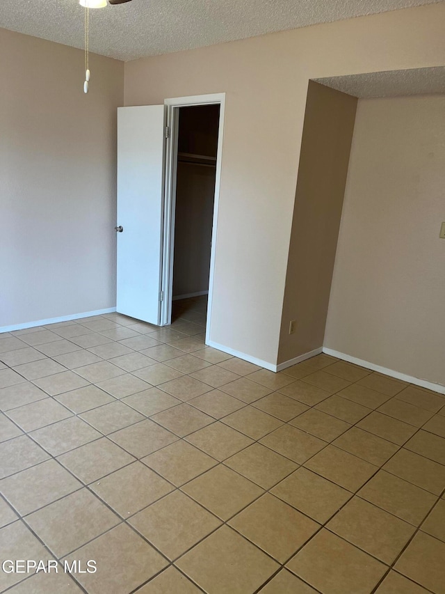 tiled empty room with a textured ceiling and ceiling fan