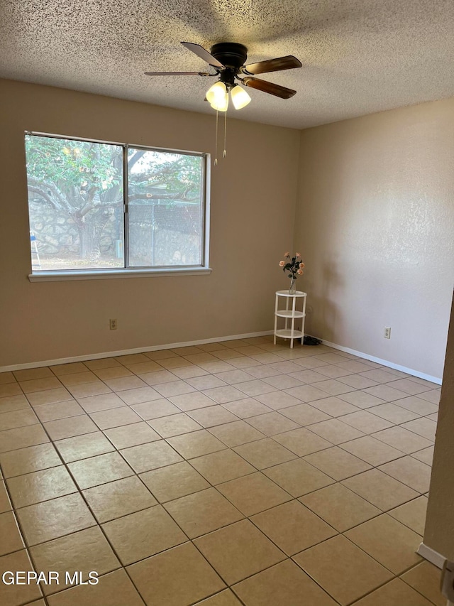 spare room with ceiling fan, a textured ceiling, and light tile patterned floors