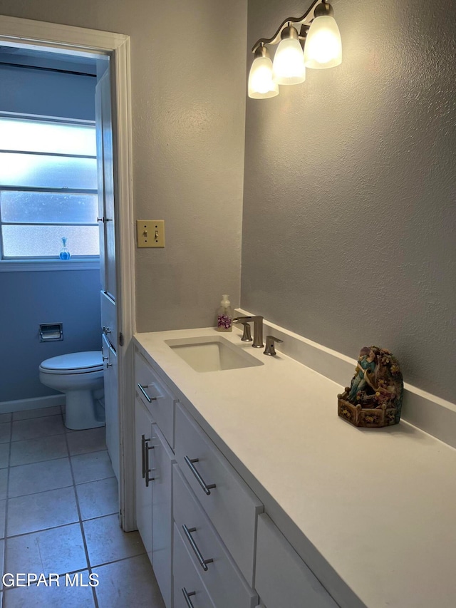 bathroom with toilet, vanity, and tile patterned floors