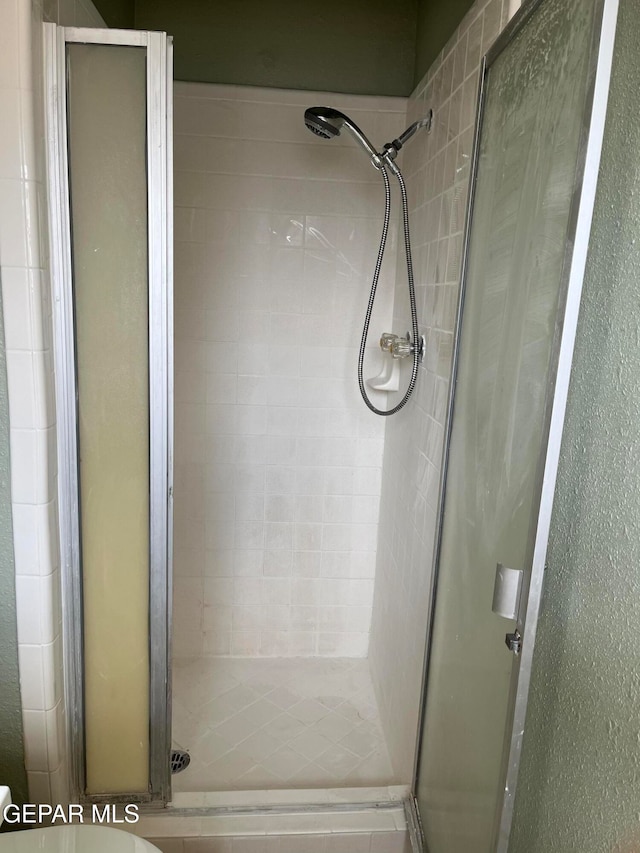 bathroom featuring toilet and a shower with shower door