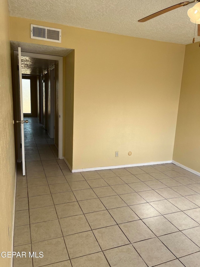 unfurnished room with light tile patterned flooring, ceiling fan, and a textured ceiling