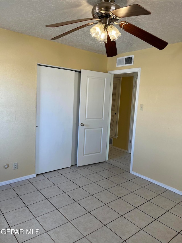 unfurnished bedroom with a closet, a textured ceiling, light tile patterned floors, and ceiling fan