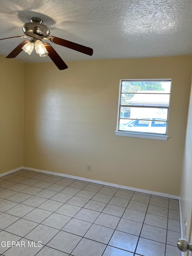 empty room with ceiling fan, a textured ceiling, and light tile patterned floors