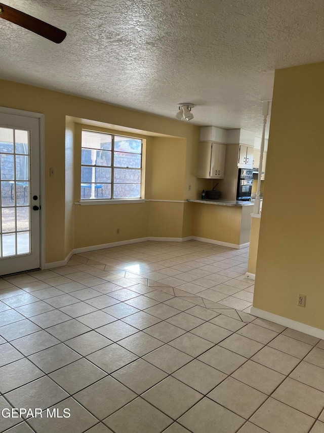 interior space featuring a textured ceiling, ceiling fan, and light tile patterned floors