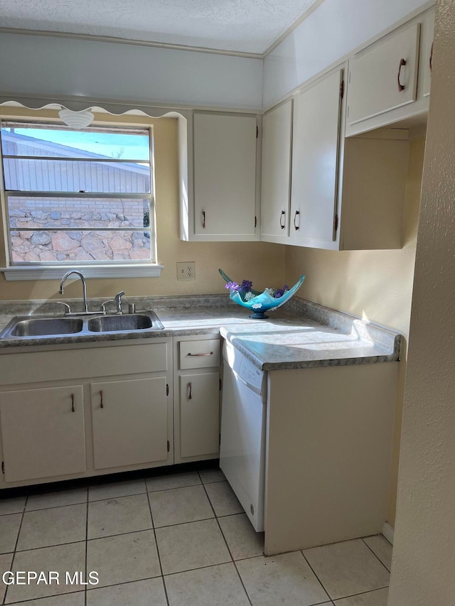 clothes washing area with cabinets, light tile patterned flooring, a textured ceiling, and sink