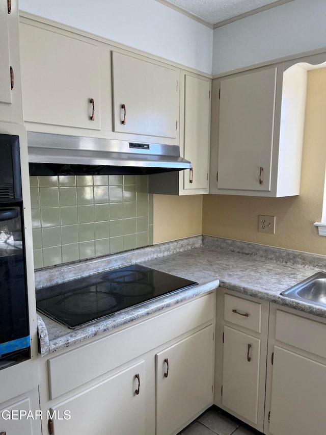 kitchen with white cabinets, black electric cooktop, sink, and light tile patterned flooring