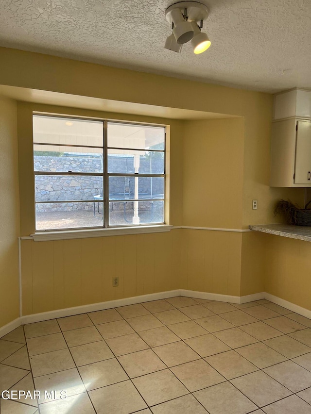 interior space with wooden walls, a textured ceiling, and light tile patterned floors