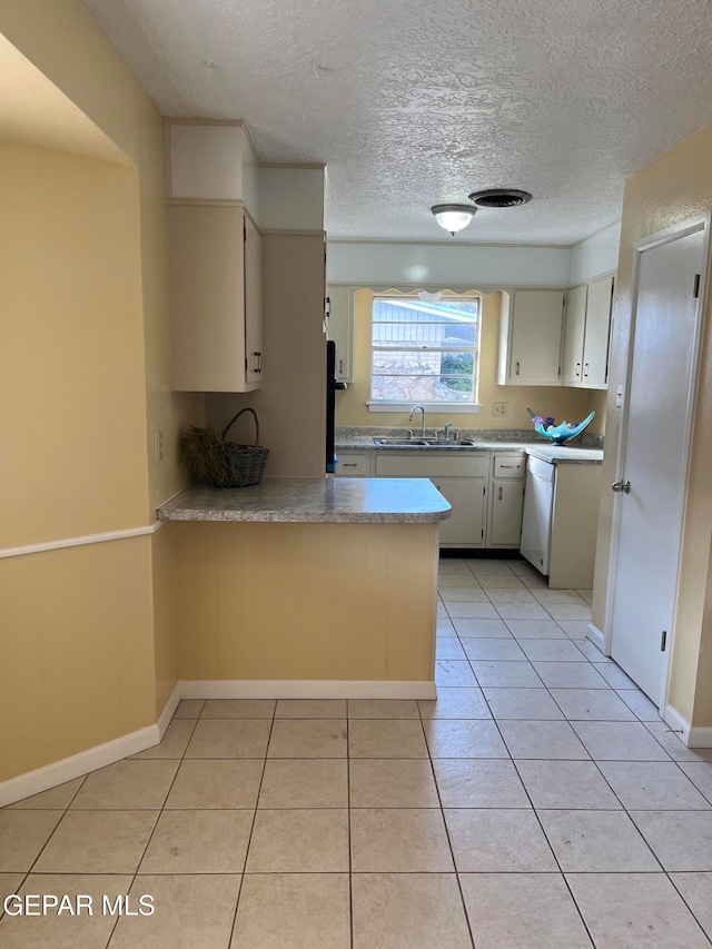 kitchen with light tile patterned flooring, sink, kitchen peninsula, a textured ceiling, and dishwasher