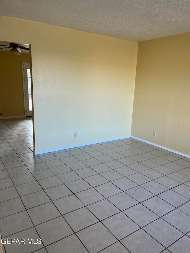 tiled empty room featuring ceiling fan and a textured ceiling