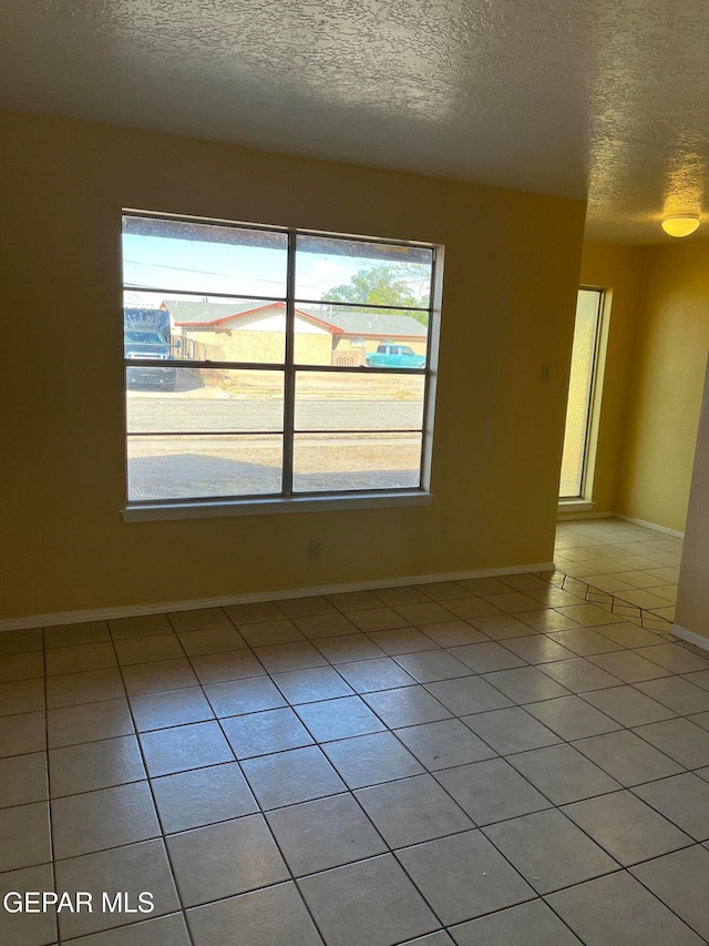 unfurnished room with light tile patterned flooring, plenty of natural light, and a textured ceiling