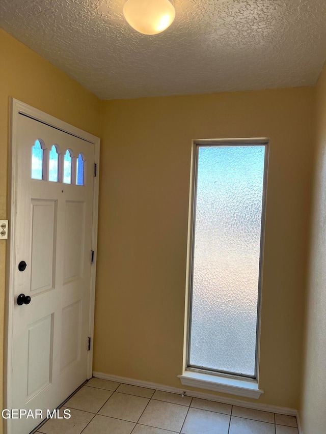 tiled entryway featuring a textured ceiling and a healthy amount of sunlight