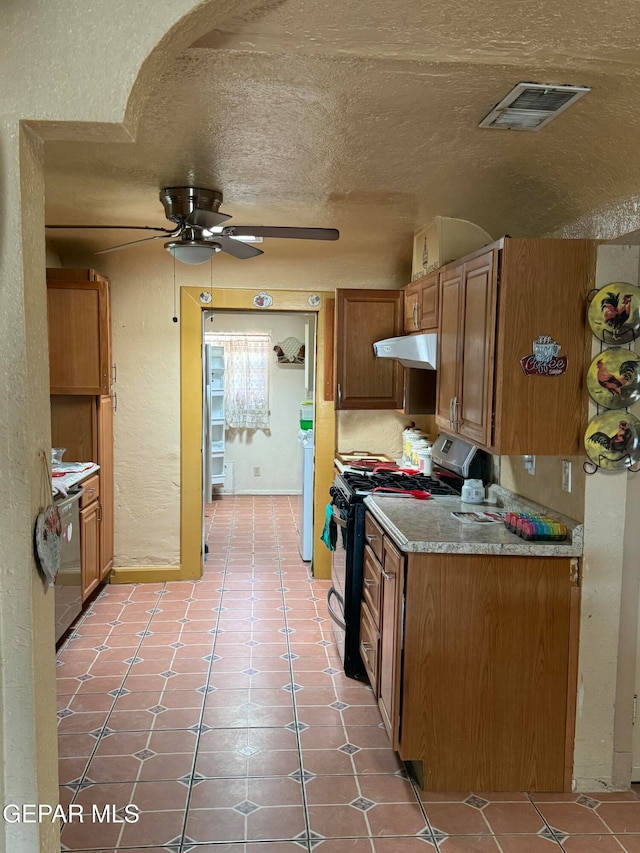 kitchen with gas range oven, light tile patterned floors, a textured ceiling, and ceiling fan